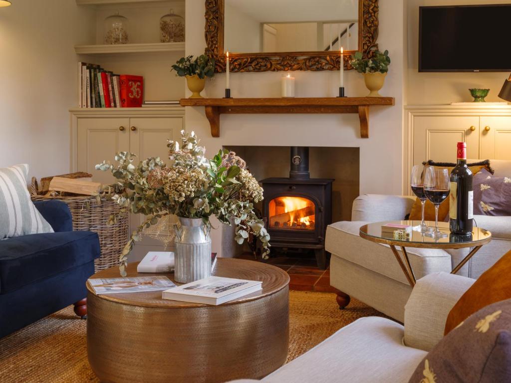 a living room with a fireplace and a table at Beehives Cottage at Woodhall Estate in Hertford