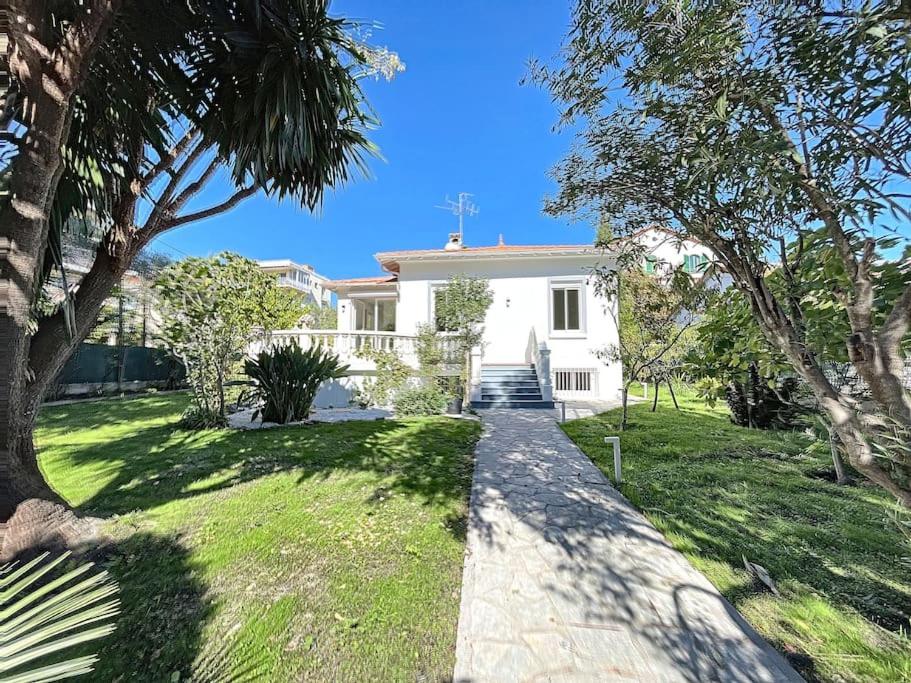 uma casa branca com um caminho na relva em VILLA VALENTINA BORD DE MER AU CALME em Antibes