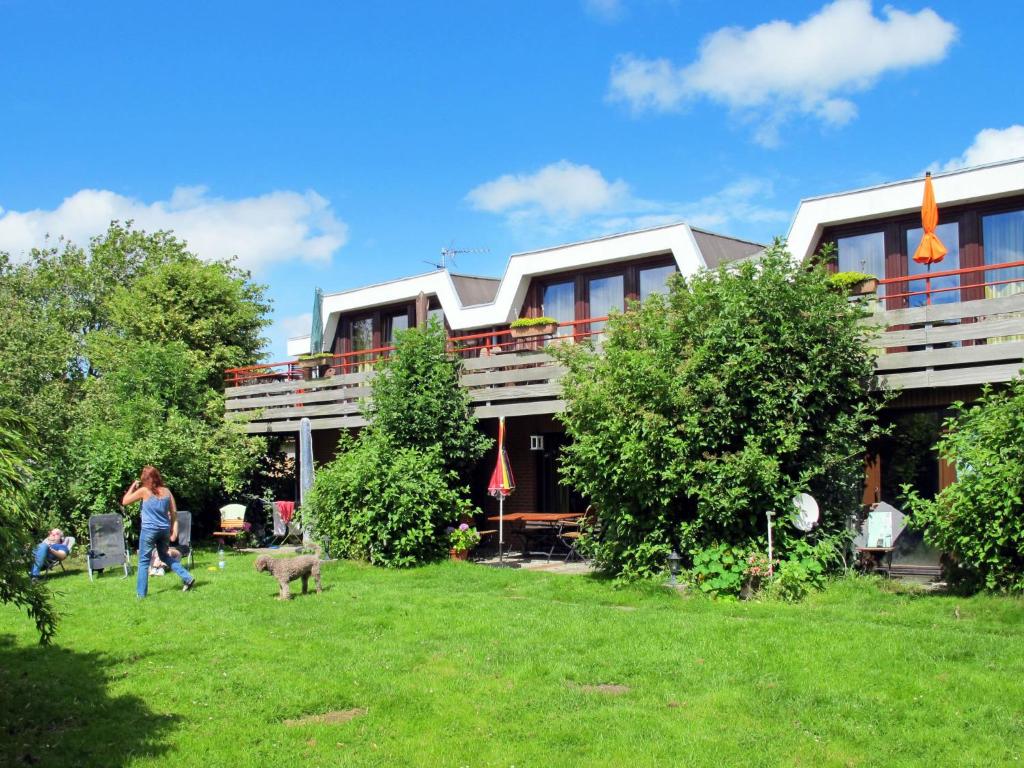 a building with people in the grass in front of it at Apartment Nordsee-Ferienhaus-1 by Interhome in Friedrichskoog