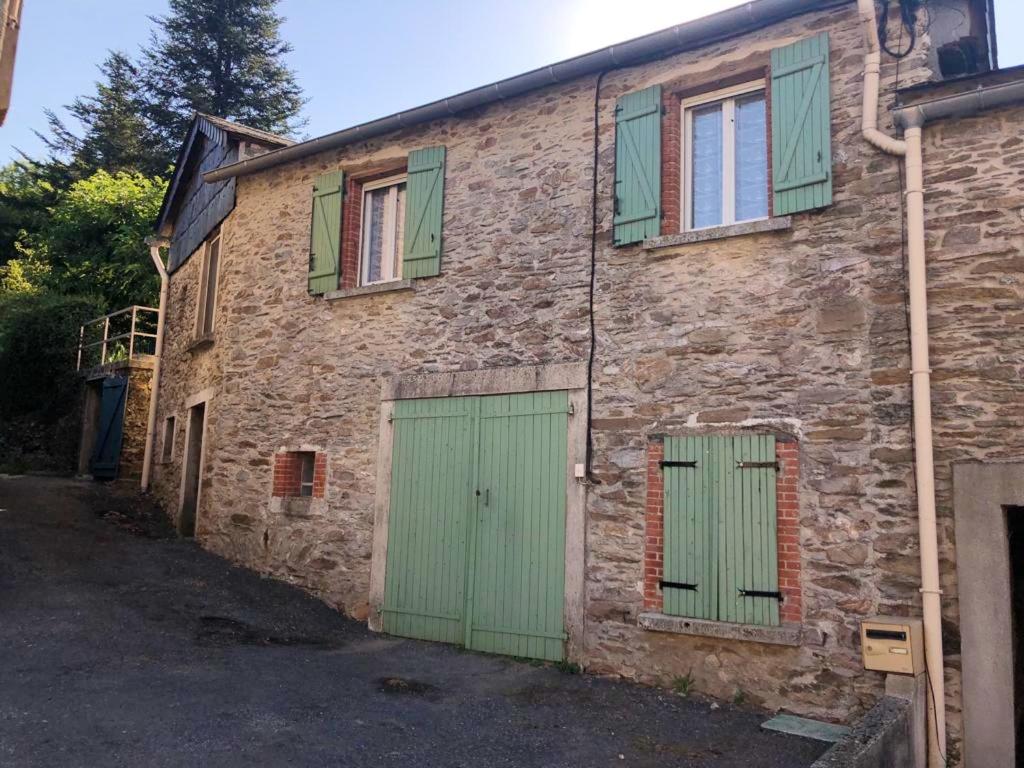 ein altes Steingebäude mit grünen Türen und Fenstern in der Unterkunft Maison de 2 chambres avec jardin amenage et wifi a Le Masnau Massuguies in Lacaze