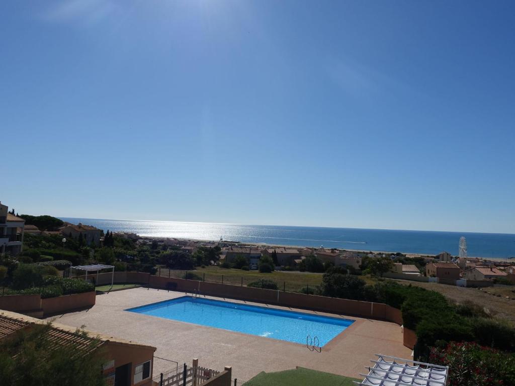 uma piscina com o oceano ao fundo em Apartment Les Eaux Vives 1 & 2-2 by Interhome em Saint Pierre La Mer