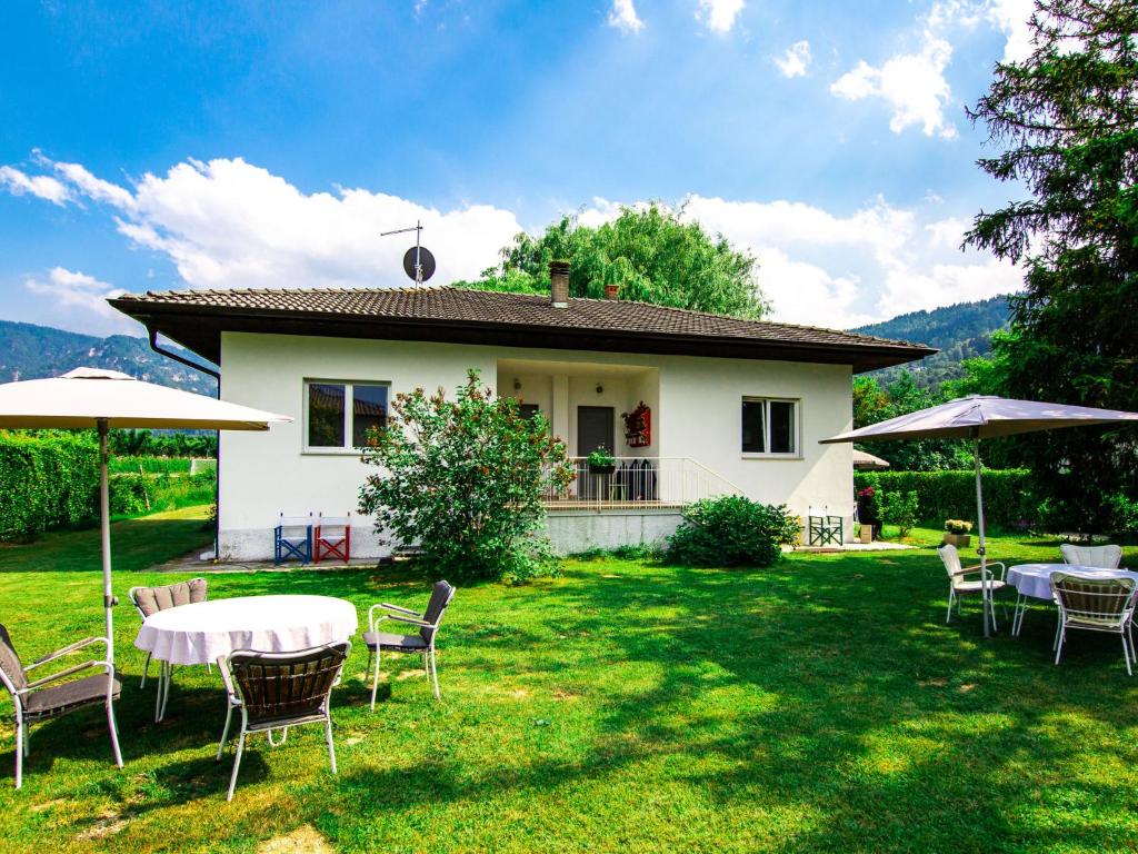 ein weißes Haus mit Tischen und Stühlen im Hof in der Unterkunft Holiday Home Villetta ai Pini-2 by Interhome in Calceranica al Lago
