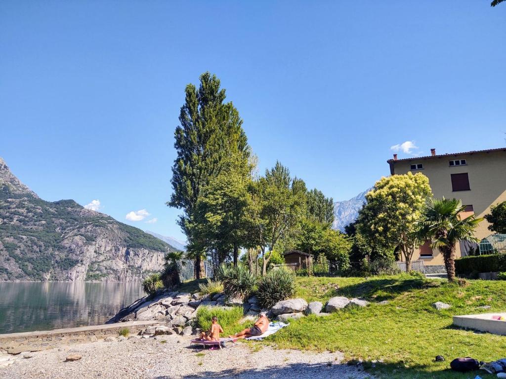 grupa ludzi siedzących na brzegu jeziora w obiekcie Apartment Punto Lago by Interhome w mieście Verceia