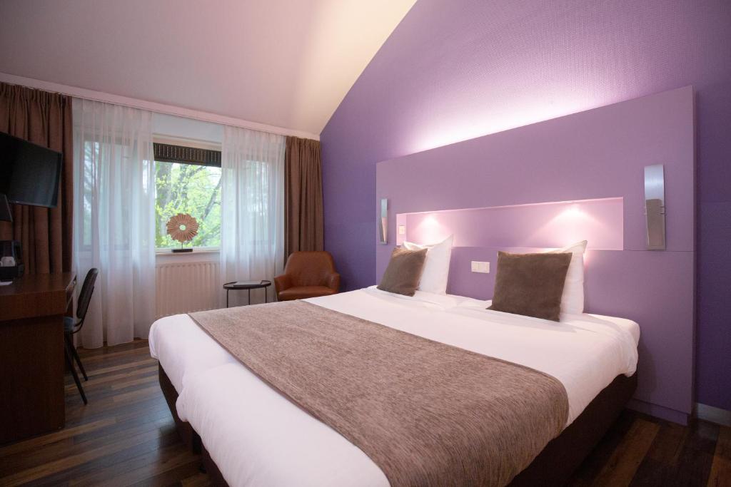 um quarto com uma cama grande num quarto roxo em 50|50 Hotel Belmont em Ede