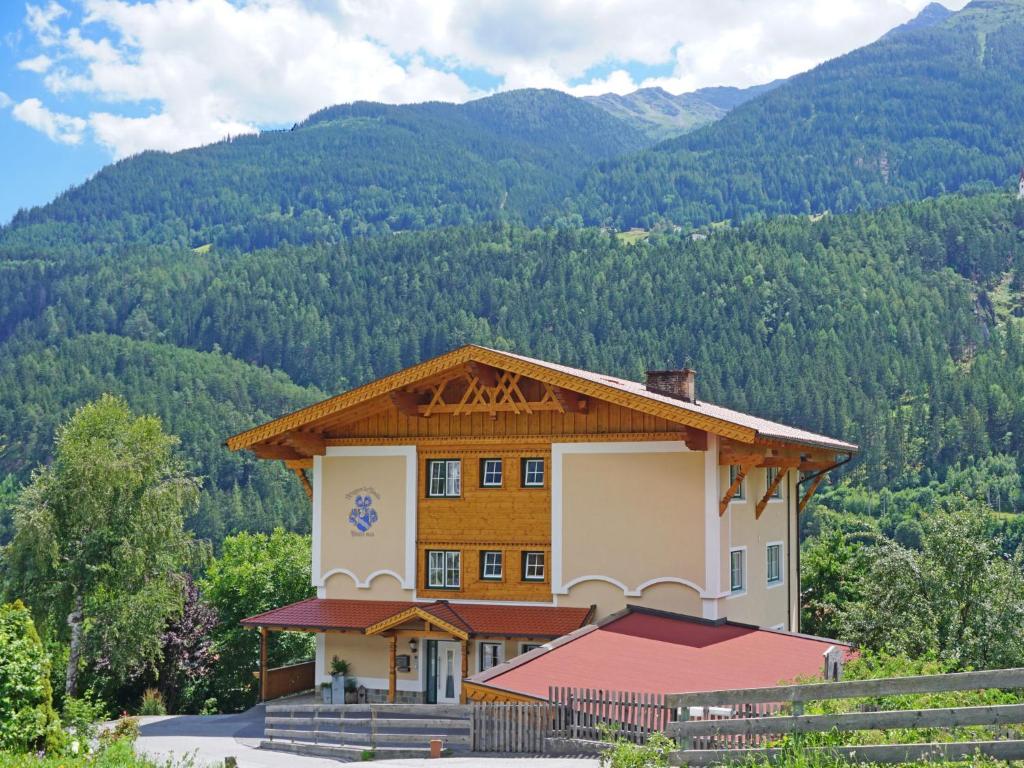 a building with a roof with mountains in the background at Apartment Pfeifer-2 by Interhome in Pians