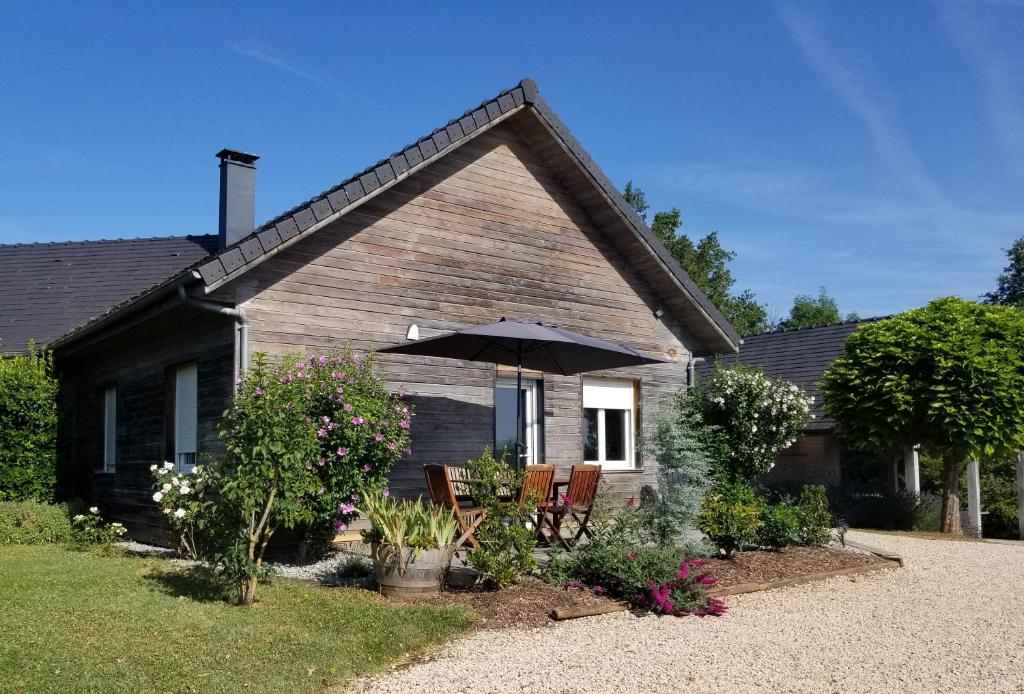 une maison avec deux chaises et un parasol dans l'établissement Gîte de la Tuillère, maison contemporaine en bois avec vue et piscine, à Saint-Aulaire