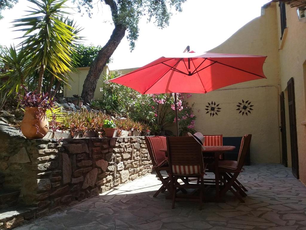 グリモーにあるGrimaud Golfe de St Tropez Var Côte d'Azurのパティオ(赤い傘付きのテーブルと椅子付)