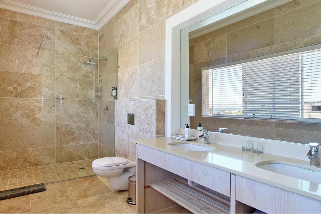 a bathroom with a sink and a toilet and a mirror at Vetho Villa in Cape Town