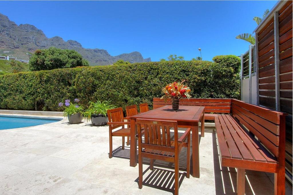a wooden table and chairs sitting next to a pool at Vetho Villa in Cape Town