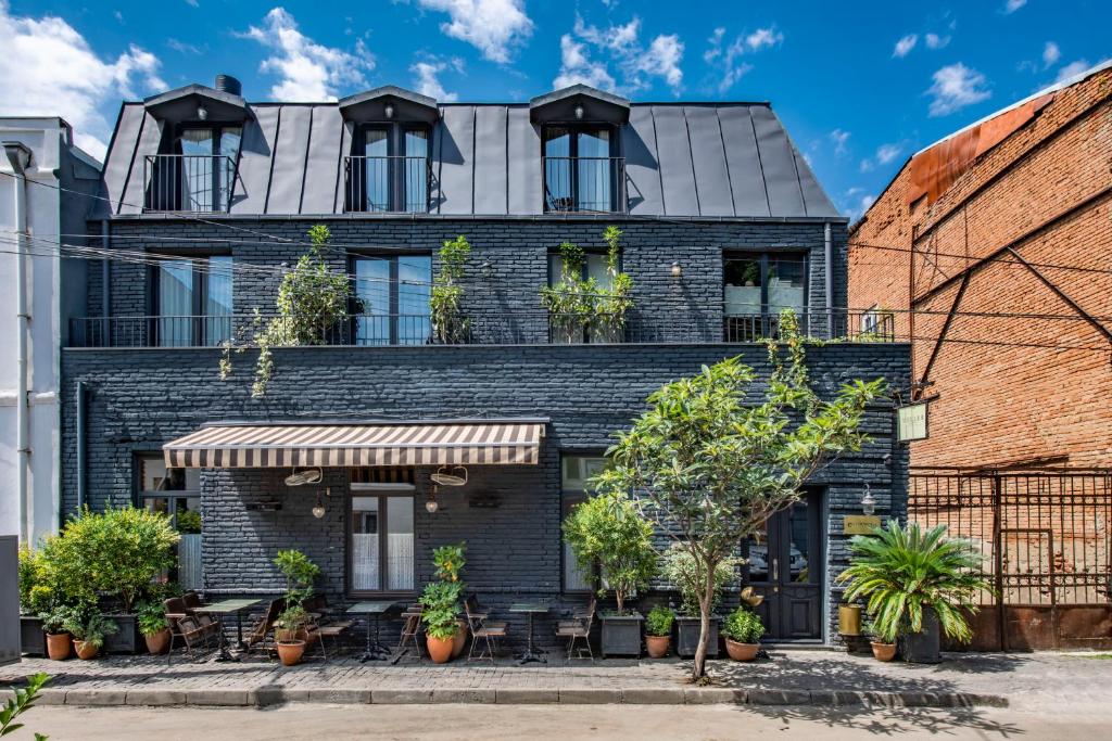 a black brick building with windows and plants at Communal Hotel Plekhanovi in Tbilisi City