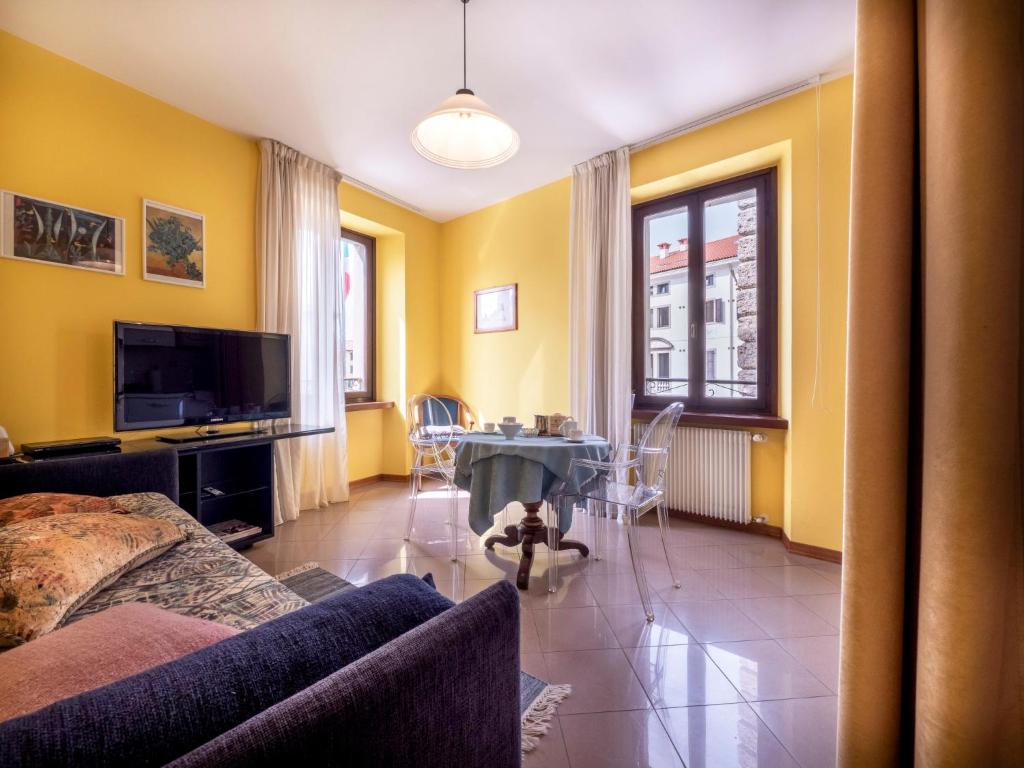 sala de estar con paredes amarillas, mesa y sillas en Apartment Squisleep-1 by Interhome, en San Daniele del Friuli
