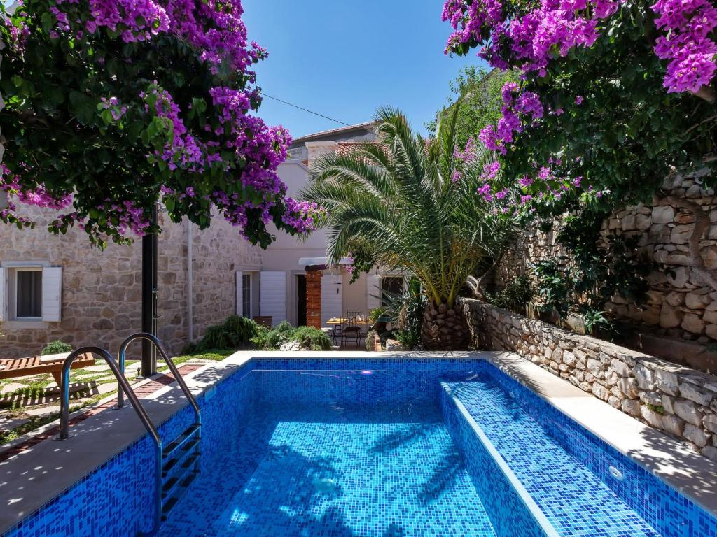 a swimming pool in a yard with trees and purple flowers at Holiday Home Marijan by Interhome in Sutivan