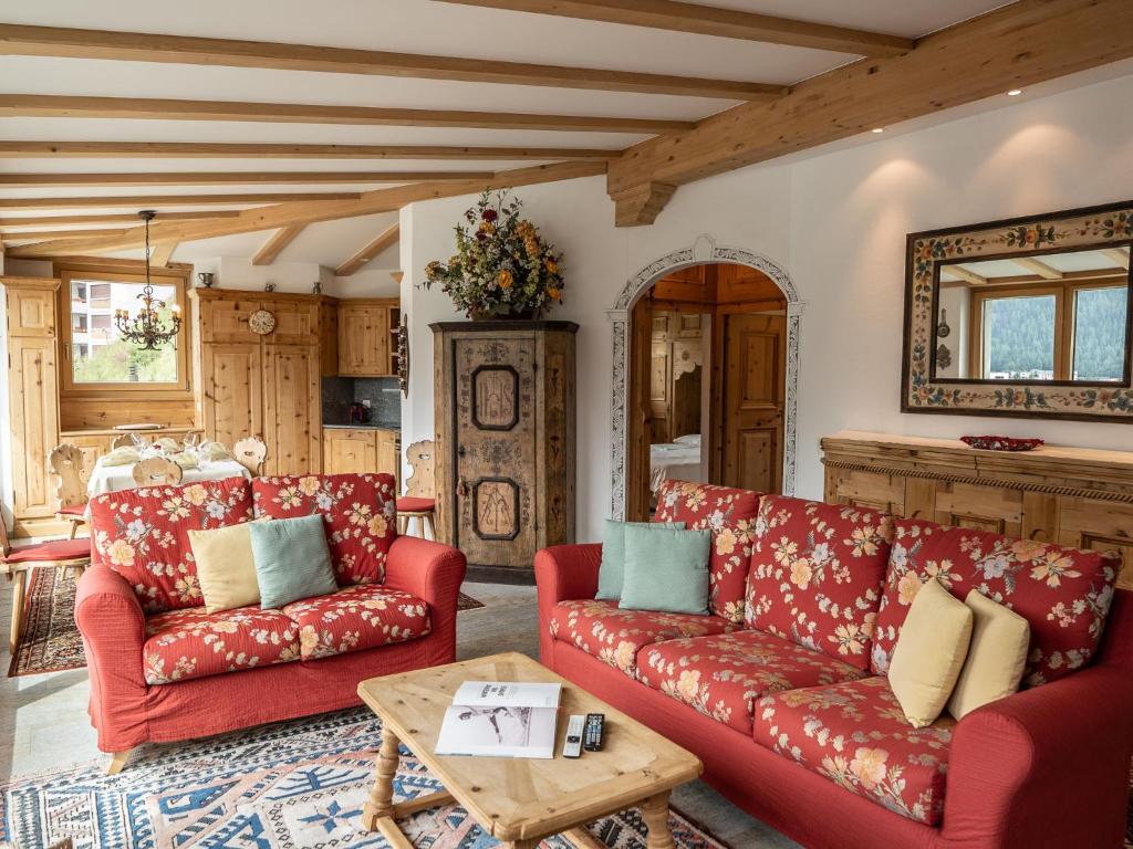 a living room with red couches and a table at Apartment Chesa Spuonda Verde 1-7 by Interhome in St. Moritz