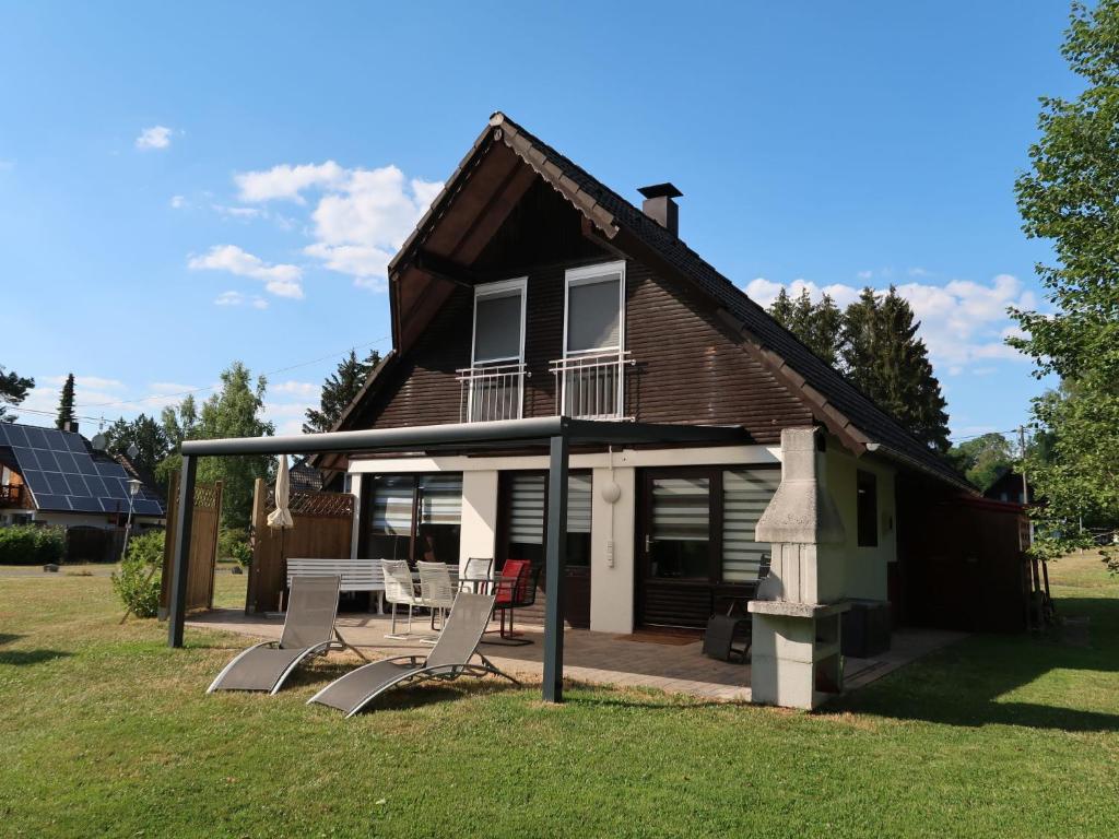 a house with a porch and two chairs in front of it at Holiday Home Ferienwohnpark Silbersee by Interhome in Frielendorf