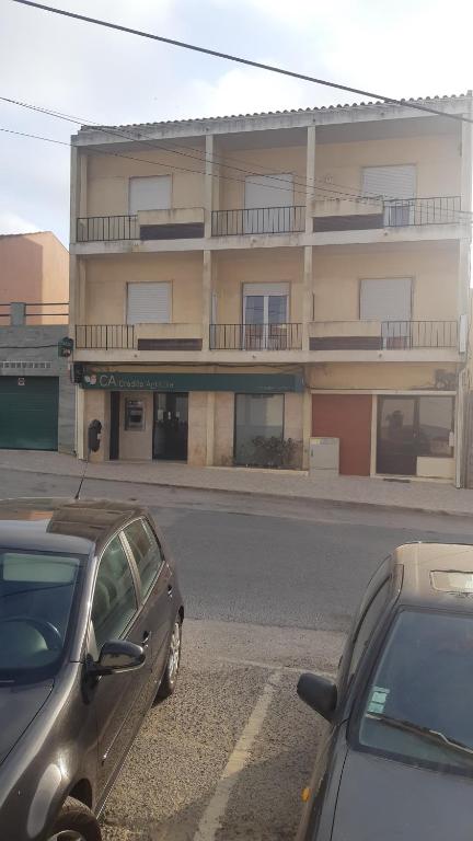 two cars parked in a parking lot in front of a building at Alojamentos S.José in Atouguia da Baleia