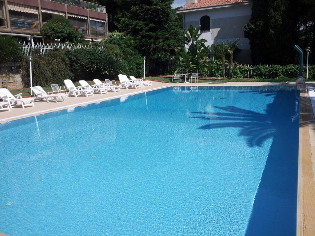 uma grande piscina azul com cadeiras e uma palmeira em Appartamento Sanremo em Sanremo