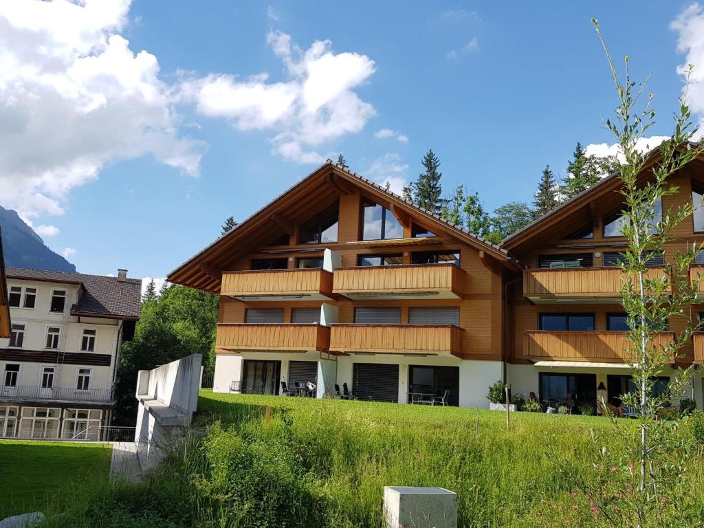 a large building on a hill with a green field at Apartment Momento by Interhome in Kandersteg