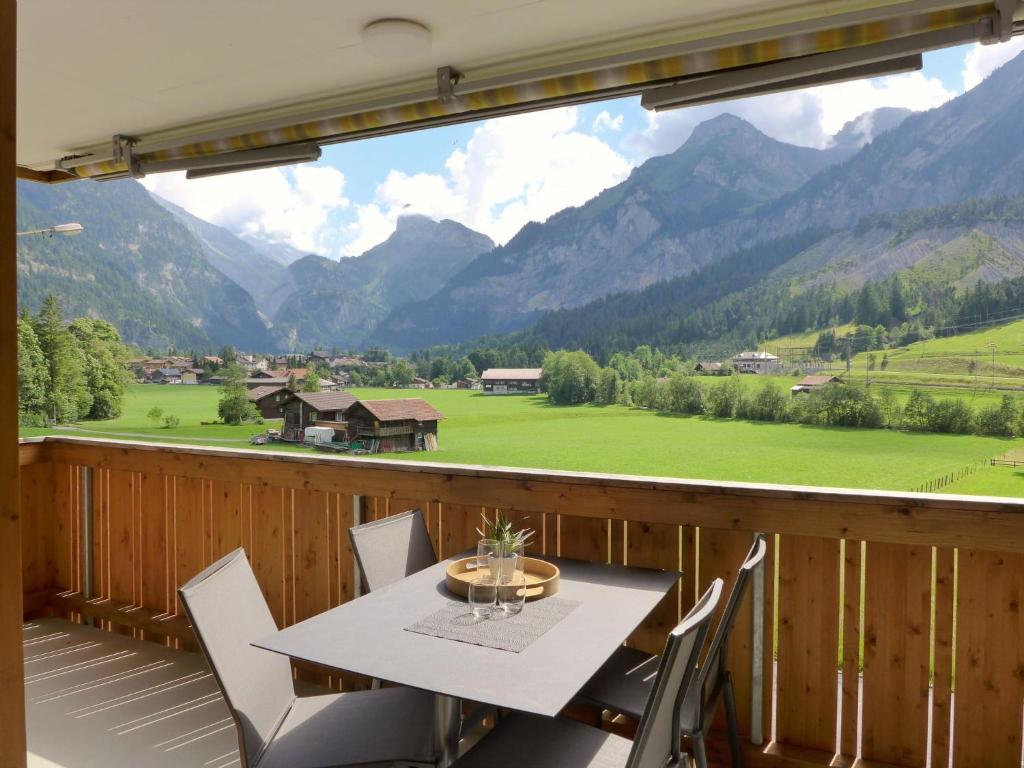 een tafel en stoelen op een balkon met uitzicht op de bergen bij Apartment Verena by Interhome in Kandersteg
