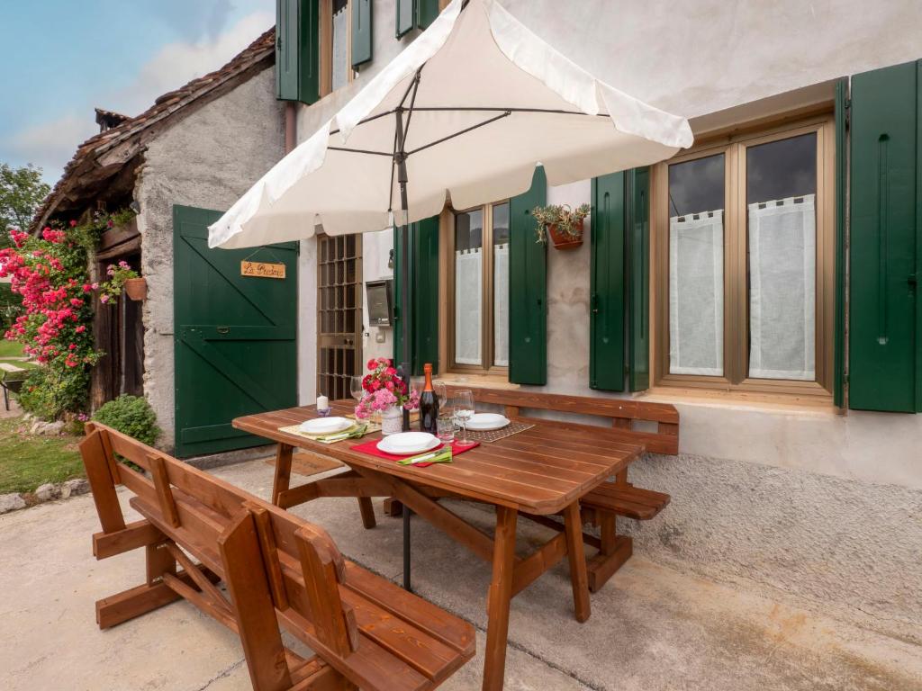 a wooden table with a white umbrella on a patio at Holiday Home La Predaia by Interhome in Barcis