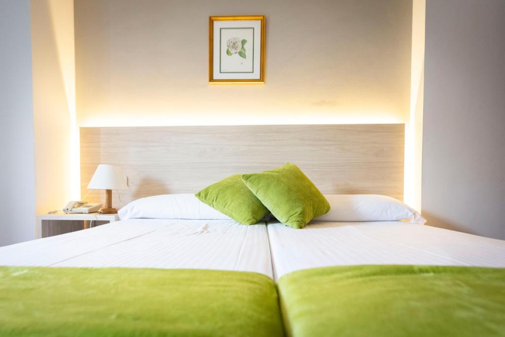 a bedroom with a bed with green pillows on it at Hotel Madrid in Pontevedra