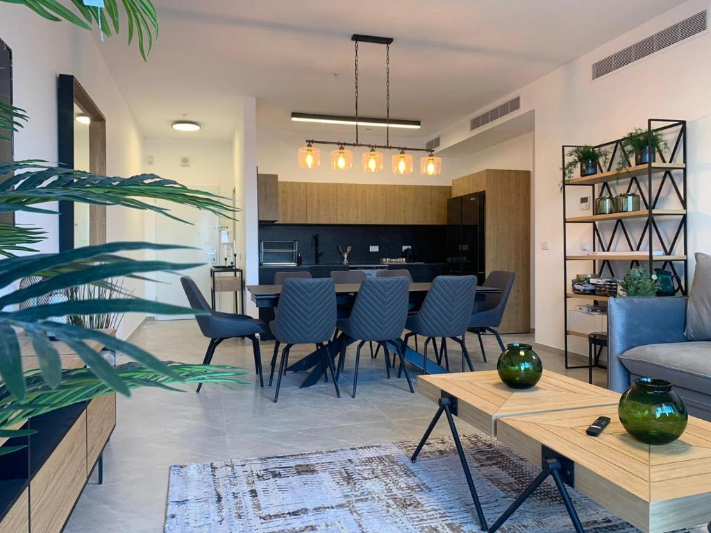 a living room with a table and chairs and a kitchen at Brand New 3 Bedroom Apartment in Shalem Tower in Jerusalem