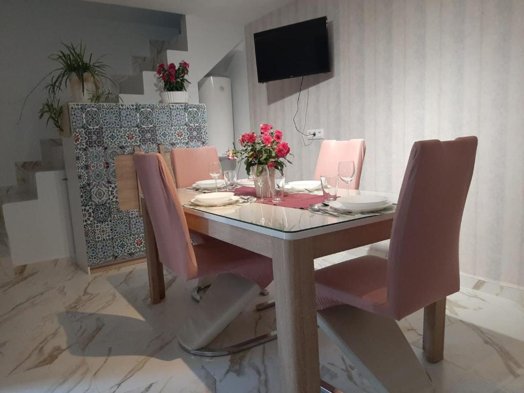 einen Esstisch mit rosa Stühlen und einem TV in der Unterkunft Sweet Home in Martos