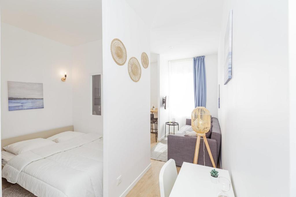 Dormitorio blanco con cama y mesa en Nice 23 M Bright And Renovated Courtyard Side, en París