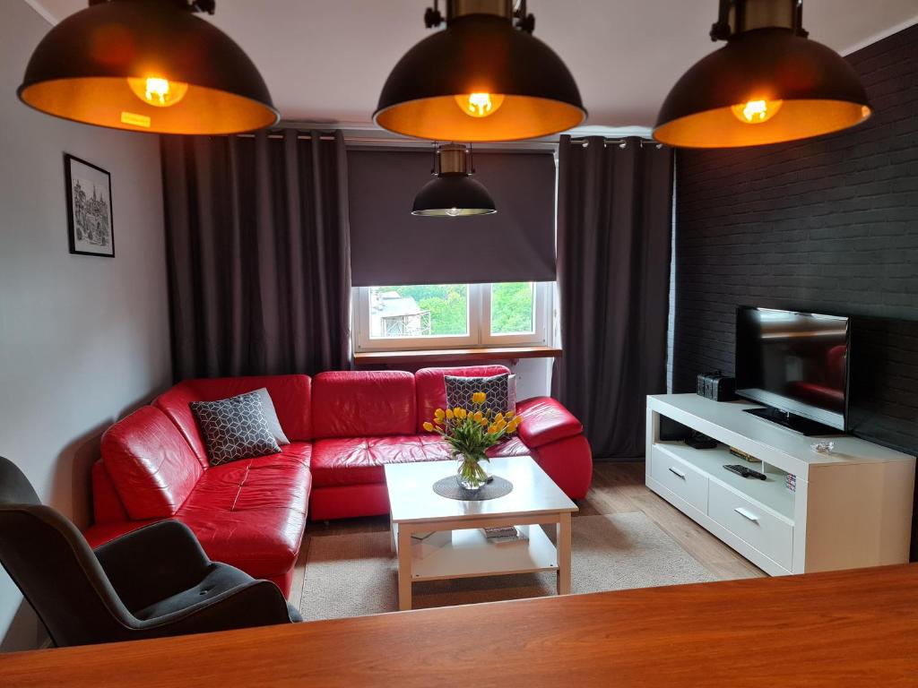 een woonkamer met een rode bank en een tv bij Apartament Wyszyńskiego Szczecin Polska in Szczecin
