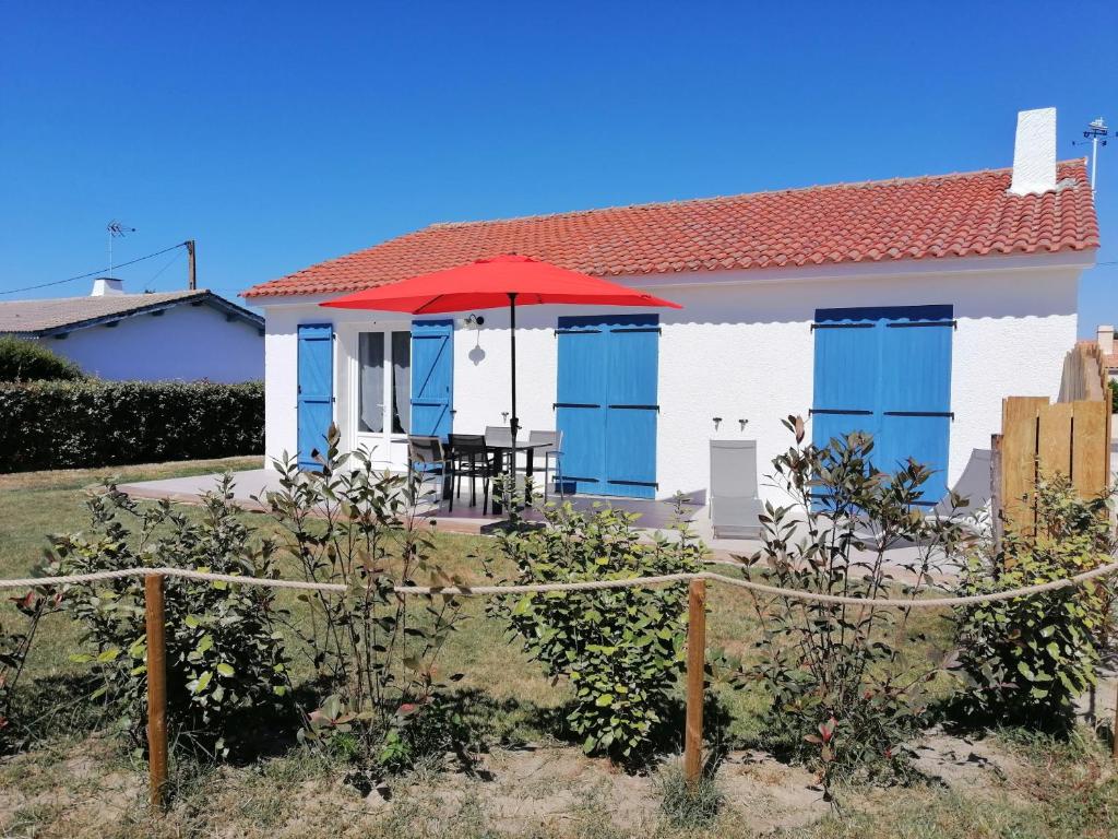 una casa bianca con finestre blu e un ombrello rosso di Le Barbatrin a Barbâtre