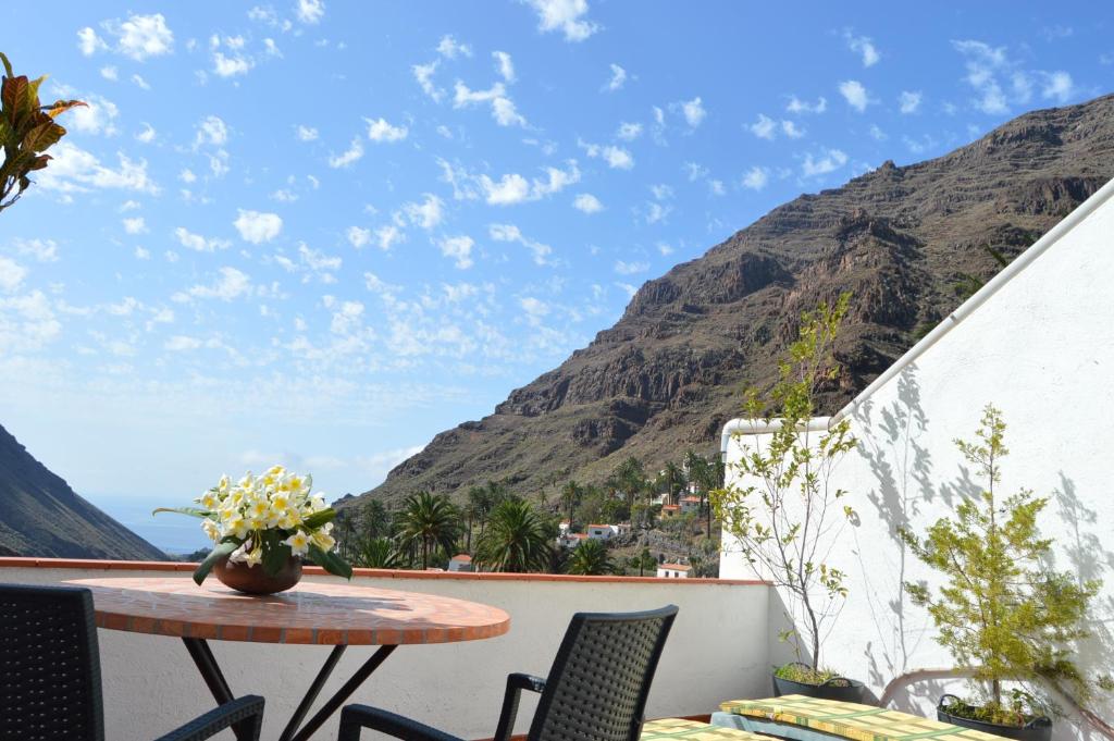 d'un balcon avec une table, des chaises et une montagne. dans l'établissement Goyo Gomera Apartments, à Valle Gran Rey