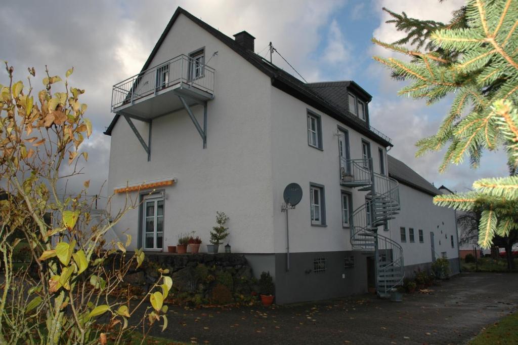 a white house with a balcony on the side of it at Ferienwohnung Luise Blum in Steffeln