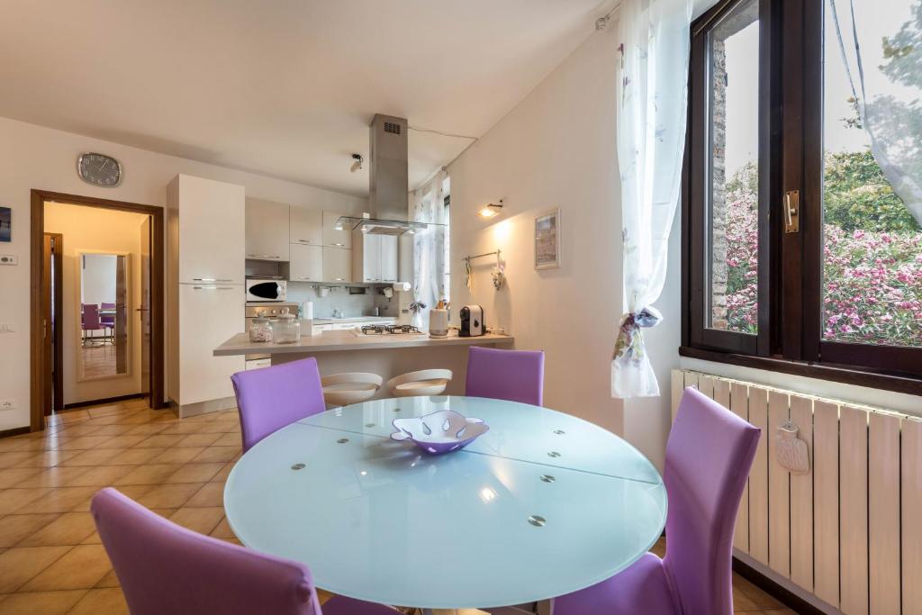 une salle à manger avec une table blanche et des chaises violettes dans l'établissement Alle Rive apartment, à Salò