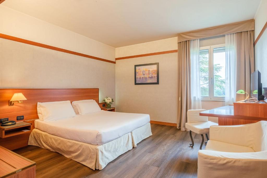 ゾーラ・プレドーザにあるSHG Hotel Bolognaのベッドとデスクが備わるホテルルームです。
