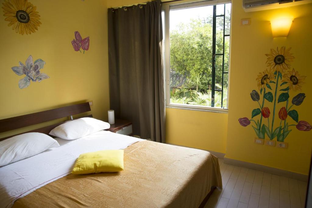 ein Schlafzimmer mit einem Bett und einem Fenster mit Blumen an der Wand in der Unterkunft B&B Rainbow in Neapel
