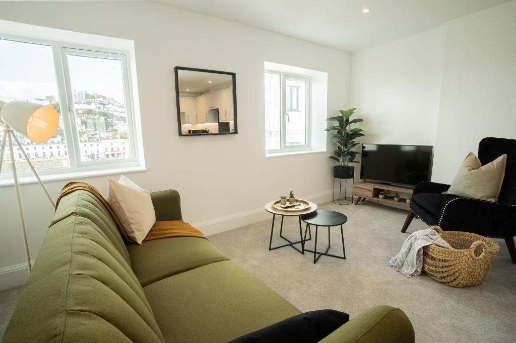a living room with a green couch and a tv at Boutique Apartments Torquay Overlooking Harbour - Near Babbacombe & Beach by Belvilla in Torquay