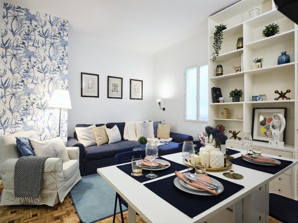 ein Wohnzimmer mit einem Tisch und einem blauen Sofa in der Unterkunft My City Home Habana I in Madrid