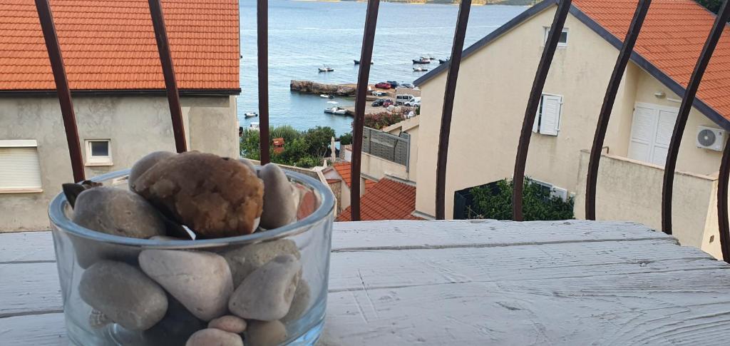 Apartmani Marijan Zavala في زافالا: جرة زجاجية من الصخور على طاولة مطلة على الماء