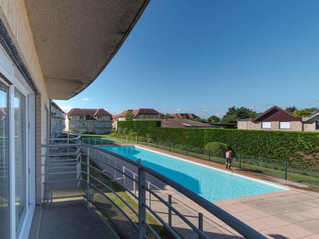 uitzicht op een zwembad vanaf het balkon van een huis bij Studio Green Garden-4 by Interhome in De Haan