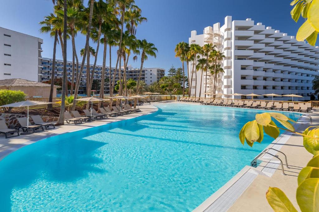 uma grande piscina com cadeiras e palmeiras em Barceló Margaritas em Playa del Inglés