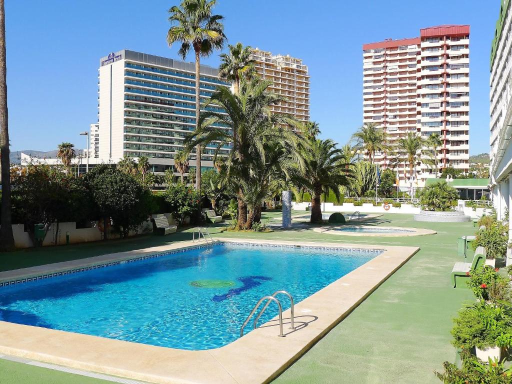 een groot zwembad met palmbomen en gebouwen bij Apartment Esmeralda-4 by Interhome in Calpe