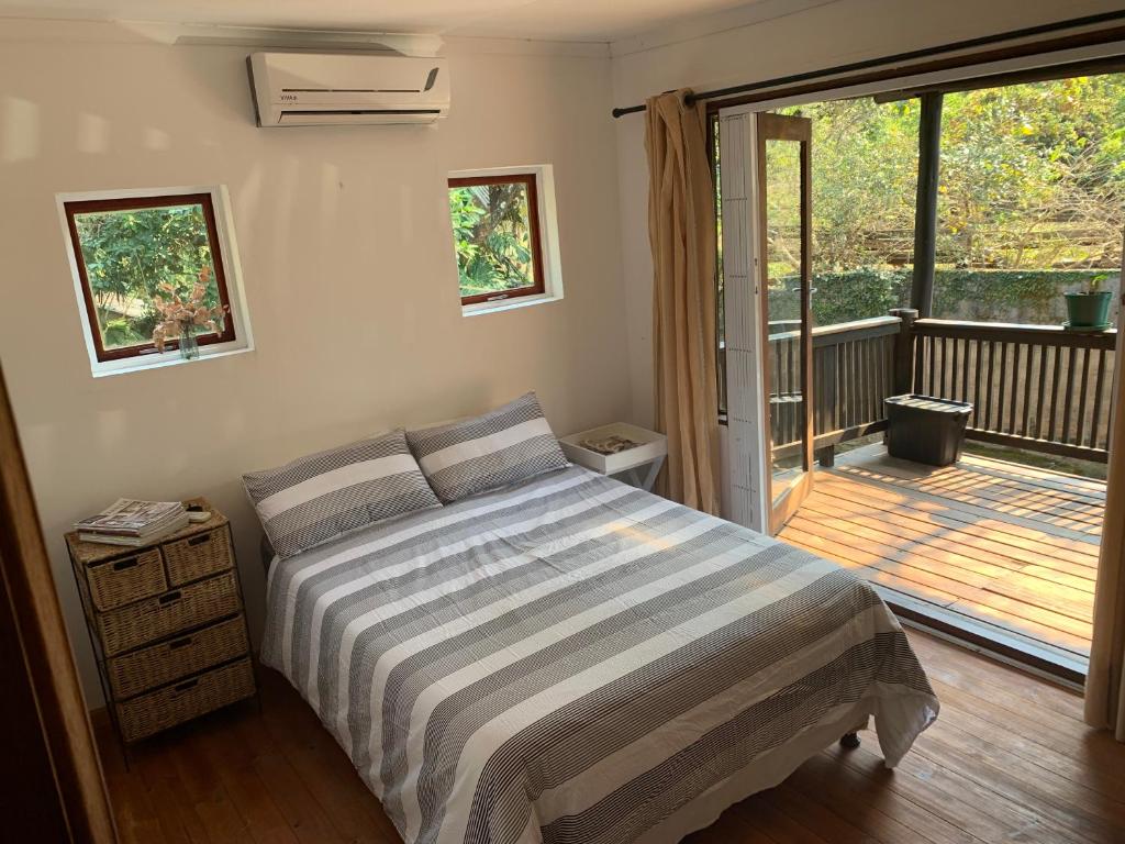 a bedroom with a bed and a sliding glass door at Jackalberry Cottage in Lobamba