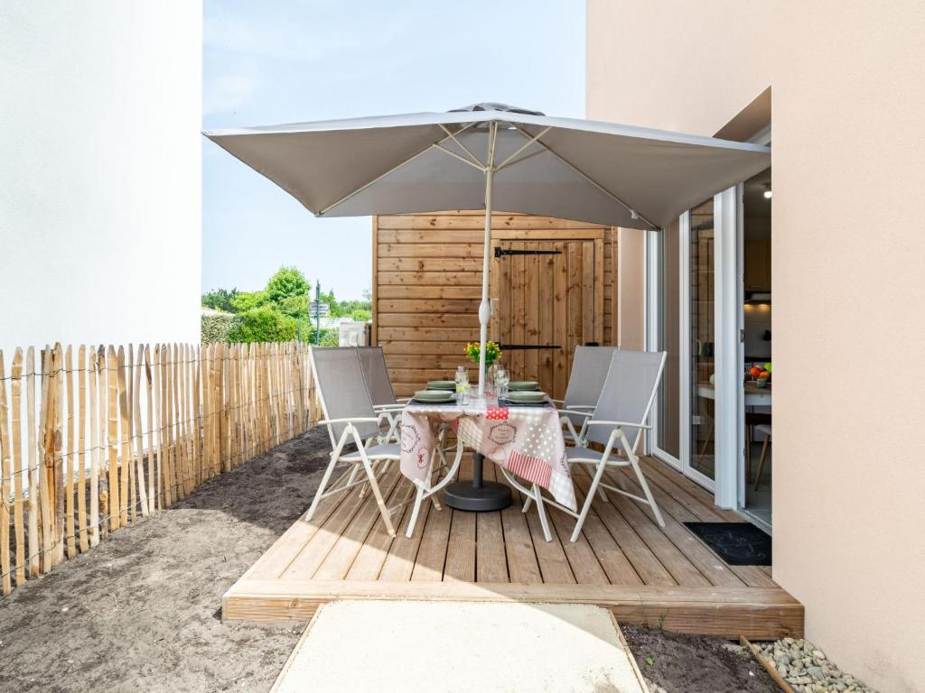a table and chairs on a deck with an umbrella at Apartment SC H01 by Interhome in Mimizan