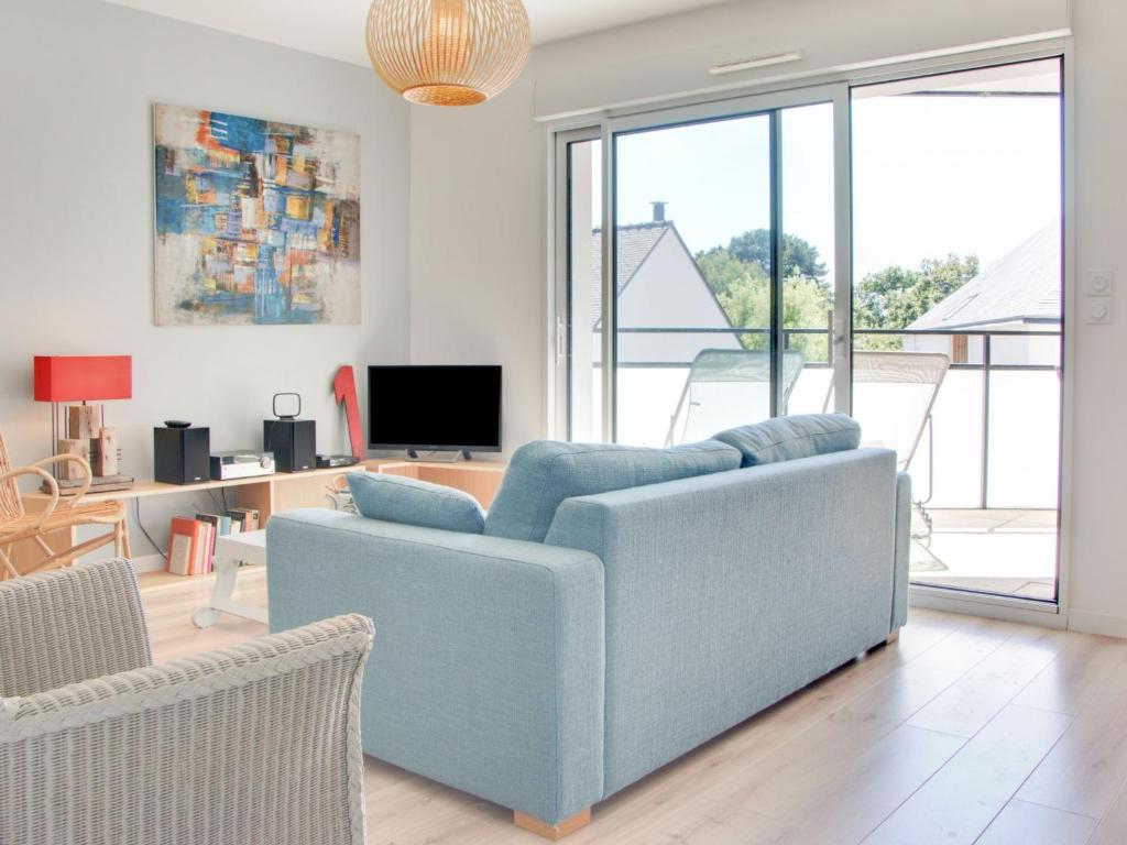 een woonkamer met een blauwe bank en een tv bij Apartment Stella Marine-2 by Interhome in Carnac