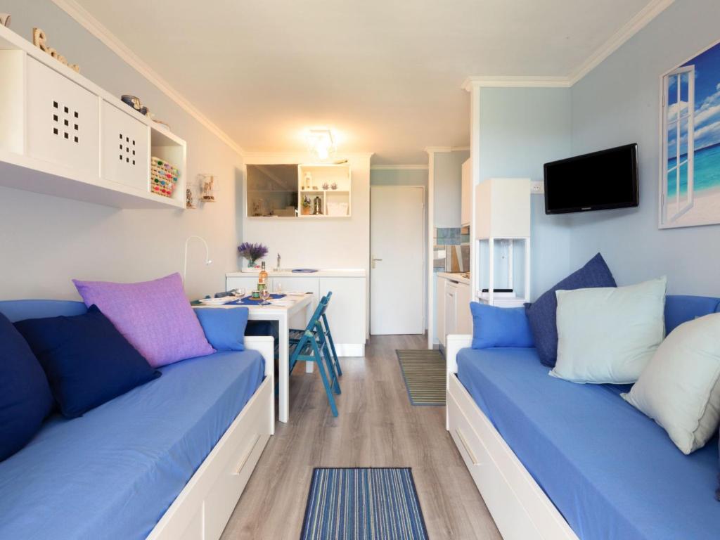 un salon avec deux canapés bleus et une cuisine dans l'établissement Apartment L'Esquinade - F6 019 by Interhome, à Saint-Raphaël