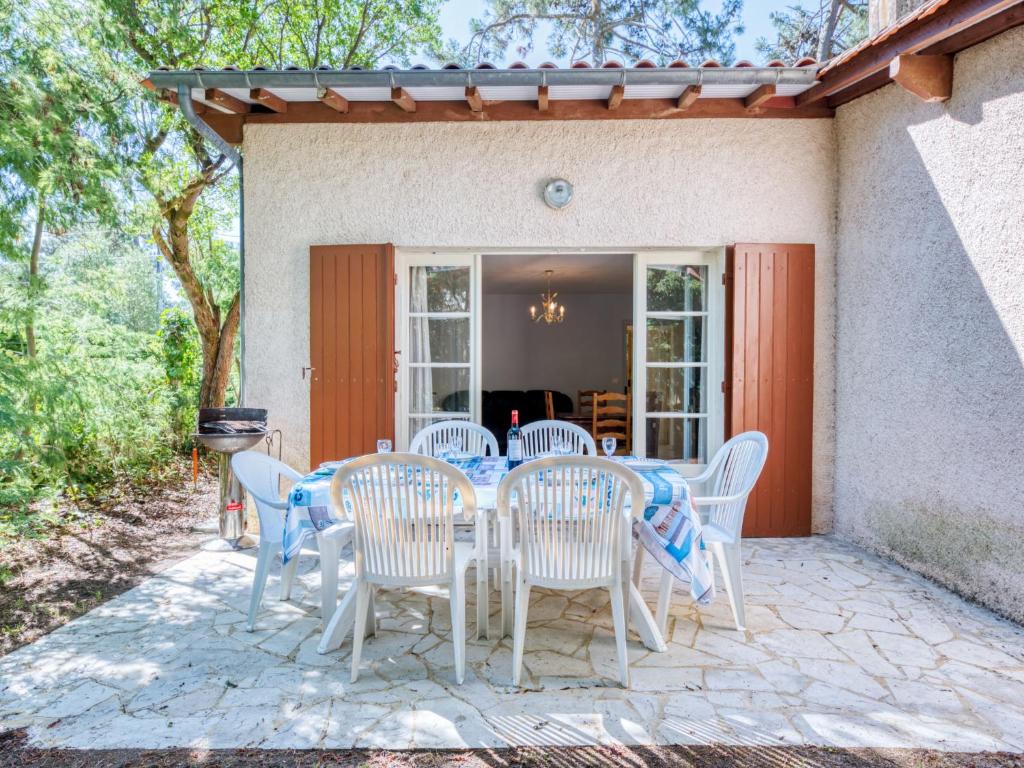 patio ze stołem i krzesłami przed domem w obiekcie Holiday Home Dominique by Interhome w mieście Lacanau-Océan
