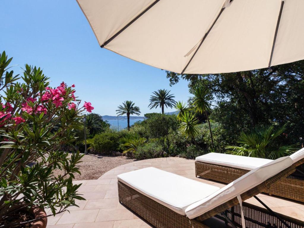 a patio with an umbrella and chairs and flowers at Holiday Home Les Résidences de Beauvallon by Interhome in Grimaud