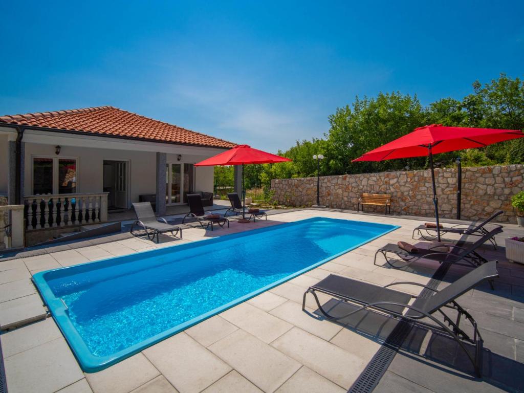 a swimming pool with chairs and umbrellas next to a house at Holiday Home Olivia by Interhome in Bribir
