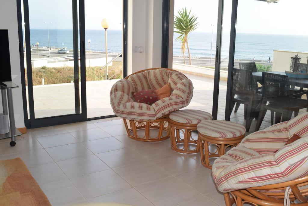 une chambre avec des chaises et une table offrant une vue sur l'océan dans l'établissement Vila Oceânica 1, à Figueira da Foz