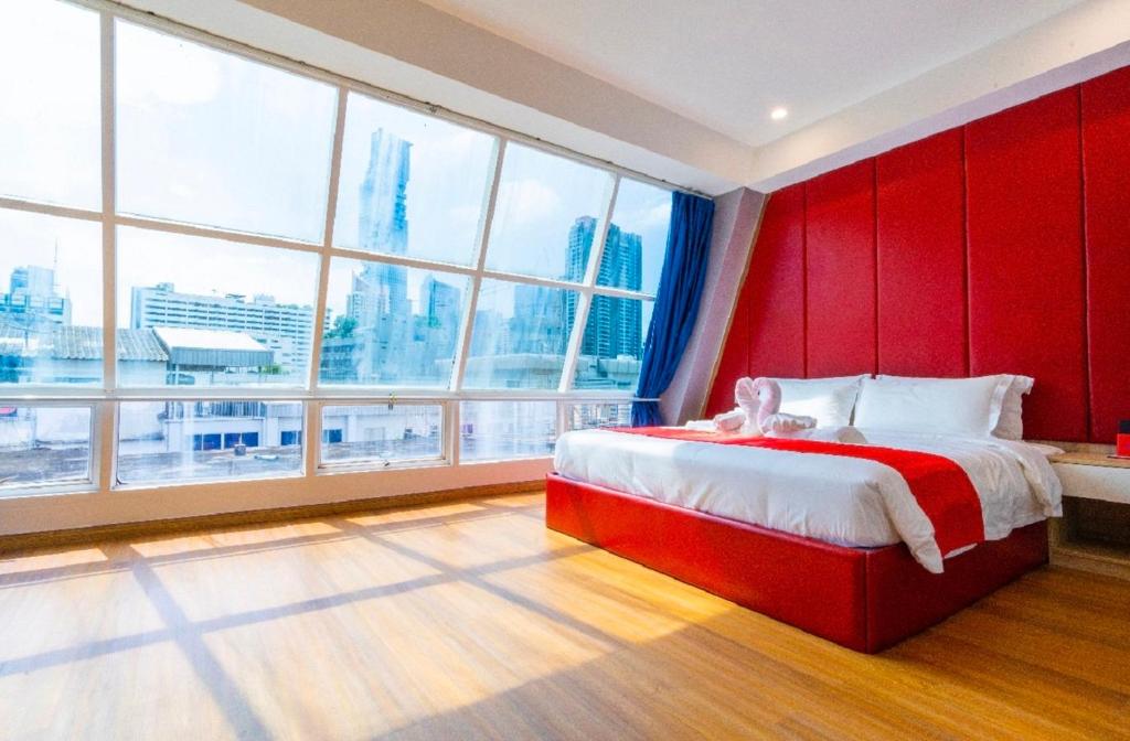 een slaapkamer met een rood hoofdeinde en grote ramen bij Sapphire Hotel Silom Bangkok in Bangkok