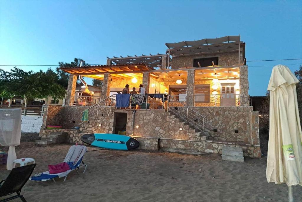 una casa en la playa con un barco delante en Maritinas Stone House & Apartment On The Beach - Happy Rentals, en Katakolon